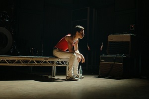 Rami Malek als Freddie Mercury, sitzt, vor Konzert