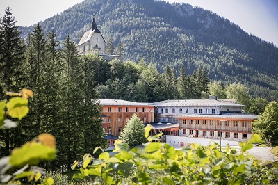 Außenansicht vom JUFA Hotel Sigmundsberg umgeben von Wald und Bergen