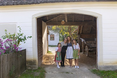 Zwei Frauen und ihre Töchter bei Muttertagsfrühschoppen mit Tracht und Dirndl in einem Torbogen im Museumsdorf Niedersulz