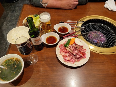 Suppe, Saucen, Getränke und Fleisch neben in den Tisch eingelassenem Grill