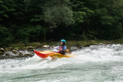 Mädchen mit Kajak im Wildwasserschwall auf der Steyr