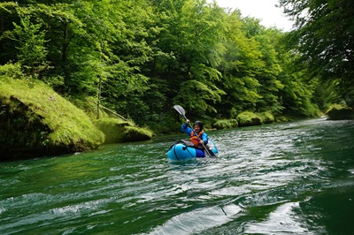 Frau paddelt mit Packraft auf der Steyr