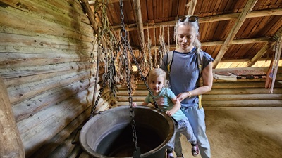 Mutter mit Kind vor einem alten Kochkessel aus der Bronzezeit
