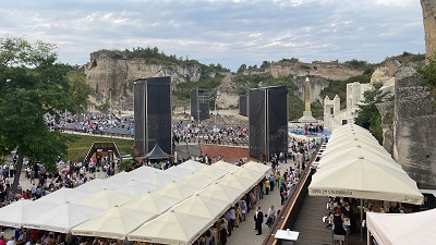 Blick von oben auf Schirmreihen und Besucher vor dem Zuschauerbereich bei der Oper im Steinbruch