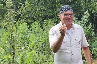 Nationalpark Ranger Manfred Rosenberger lächelnd mit einem Stück Brennessel in der Hand.