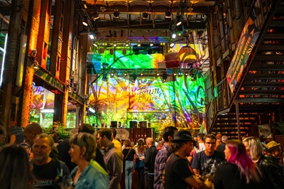 Menschen in der Halle der Ottakringer Brauerei beim Vienna Rumfestival mit bunt beleuchteten Wänden