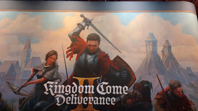 Das Artwork und Logo von Kingdom Come Deliverance II auf eine Wand gedruckt