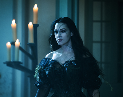 Monica Bellucci als Delores in schwarzem Kleid vor Kerzen in Beetlejuice Beetlejuice.