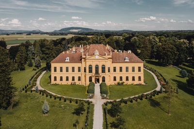 Drohnenaufnahme von Schloss Eckartsau umgeben vom Schlosspark und dem Wald der Donau-Auen.