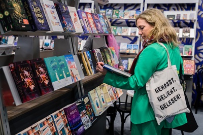 Frau steht vor einem Bücherregal und hat ein Buch in der Hand bei der Langen Nacht der Bücher bei der Buch Wien.