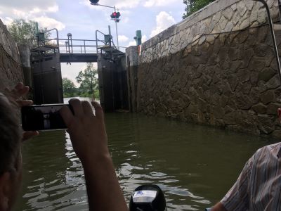 Eine Schleuse im Bata-Kanal mit niedrigem Wasserstand. Zu beiden Seiten hoch aufragende Steinmauern. Das Schleusentor schließt sich gerade.