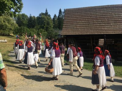 Eine Gruppe von Menschen in historischer Tracht. Die meisten davon Frauen mit weißen Röcken und Blusen, mit bunten Schürzen, Westen und Kopftüchern.