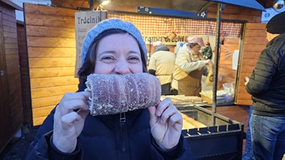 Frau mit Trdelník vor dem Mund bei einem Weihnachtsmarkt in Brünn