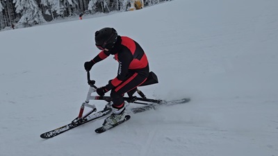 Frau im Rennanzug fährt mit dem Skibob eine Kurve.