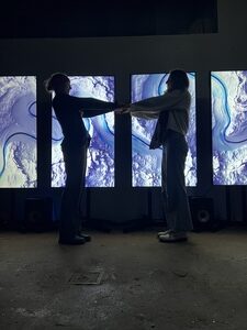 Zwei Frauen halten sich die Hände bei Lichtinstallation helix nebula bei der khroma AUsstellung in Wien