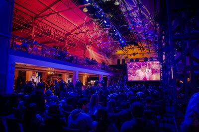 Zuschauer sitzen vor einem großen LED Screen und schauen Football bei der Super Bowl Party in der METAstadt in Wien