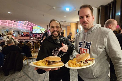 Zwei Männer mit einem Teller mit Burgern und Potatoe Wedges bei der Super Bowl Party im Vienna Marriott